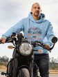Person wearing a blue hoodie with a graphic design on a motorcycle
