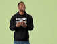 Man wearing a black hoodie with text, holding a phone on a light green background