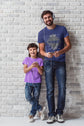 Man and child standing against a white brick wall, both wearing headphones.