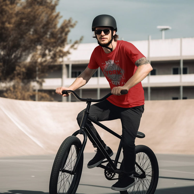 Man riding a black bicycle on a concrete surface with a building and tree in the background
