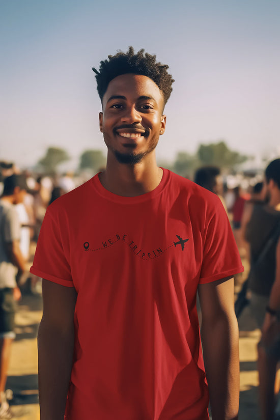 Man wearing a red t-shirt with text and graphics, standing outdoors with a crowd in the background.