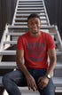 Man wearing a red t-shirt with text sitting on a staircase.