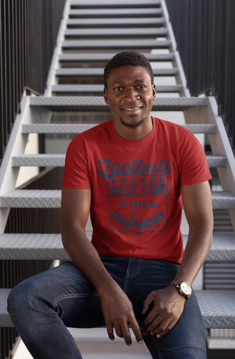 Man wearing a red t-shirt with text sitting on a staircase.