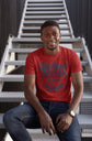 Man wearing a red t-shirt with text sitting on a staircase.