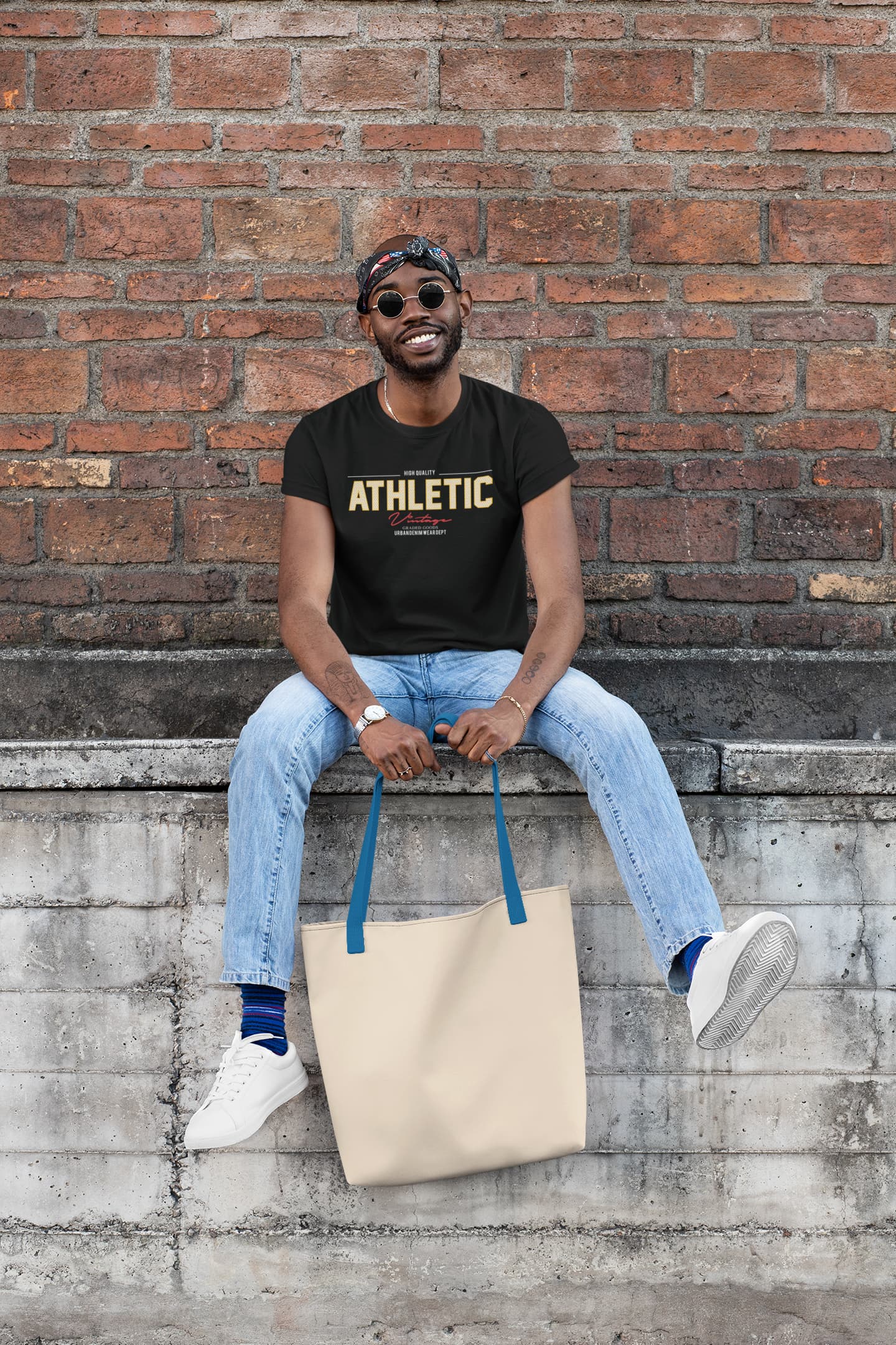 Man sitting on a ledge with a tote bag against a brick wall