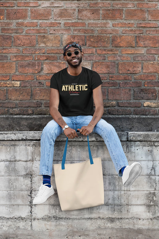 Man sitting on a ledge with a tote bag against a brick wall