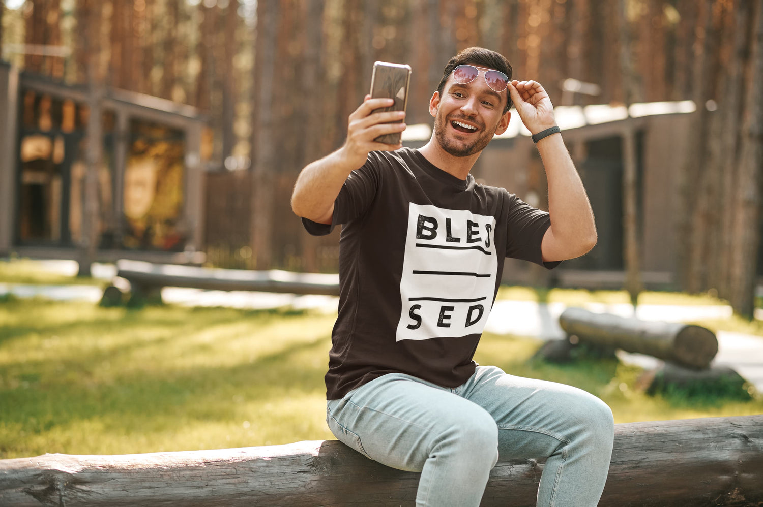 Man taking a selfie outdoors wearing a black t-shirt with text.