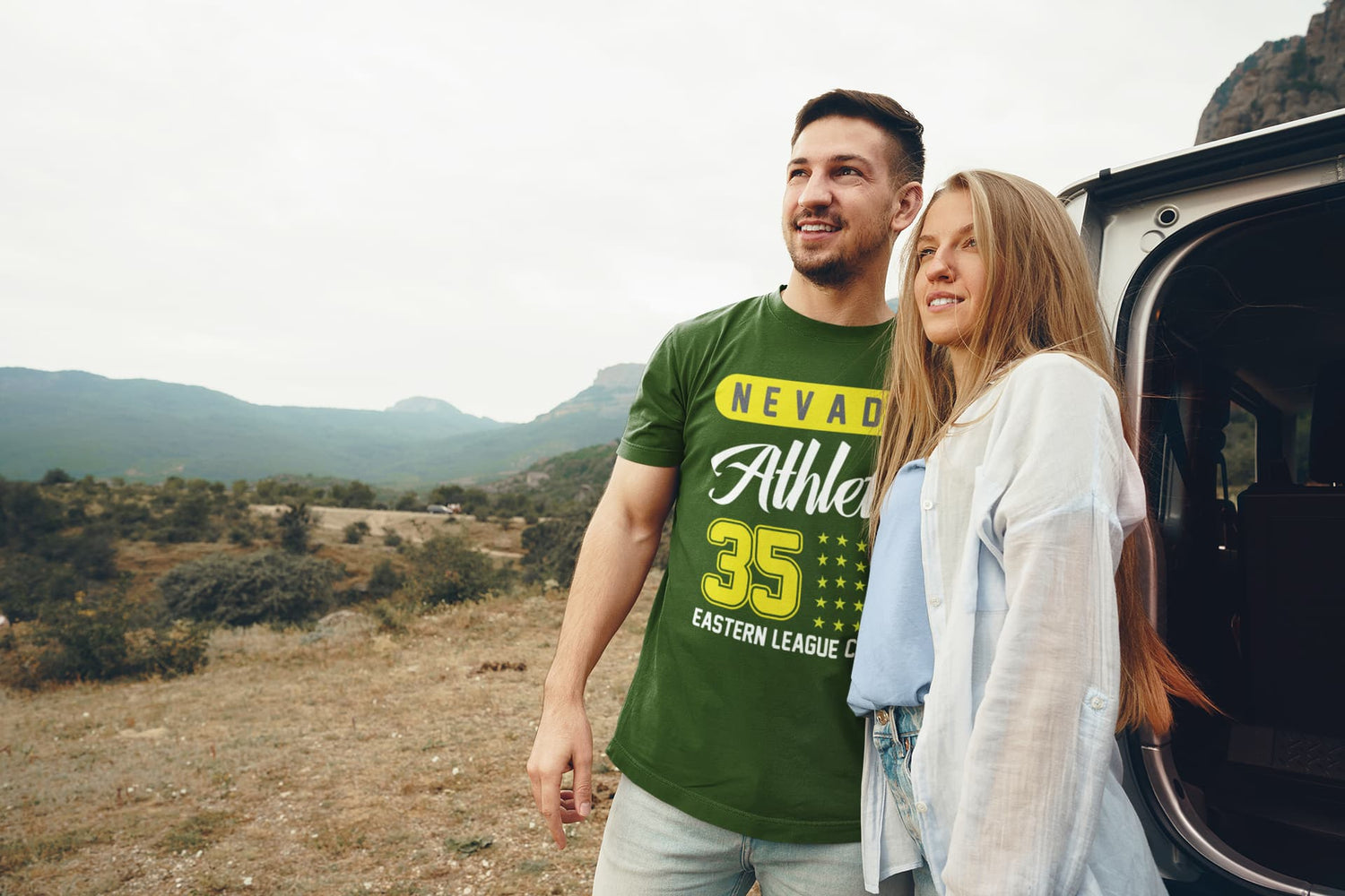 Man and woman standing next to an open car door in a scenic outdoor setting.