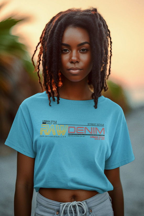 Person wearing a blue t-shirt with text and graphics, standing against a blurred natural background