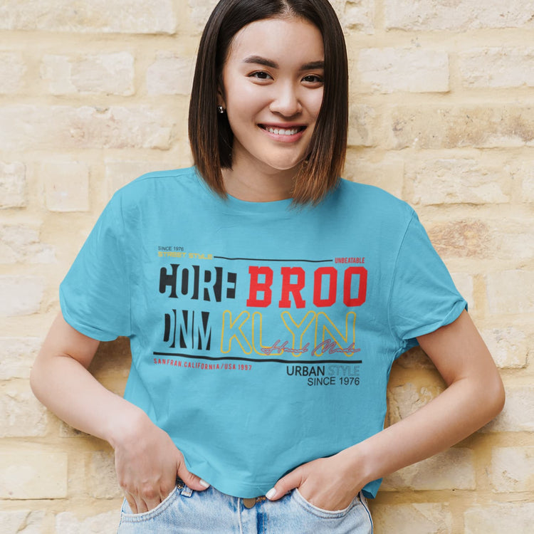 Person wearing a blue t-shirt with colorful text against a beige brick wall