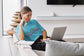 Woman sitting on a couch using a laptop in a modern living room.