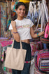 Woman holding a beige tote bag in a colorful market setting