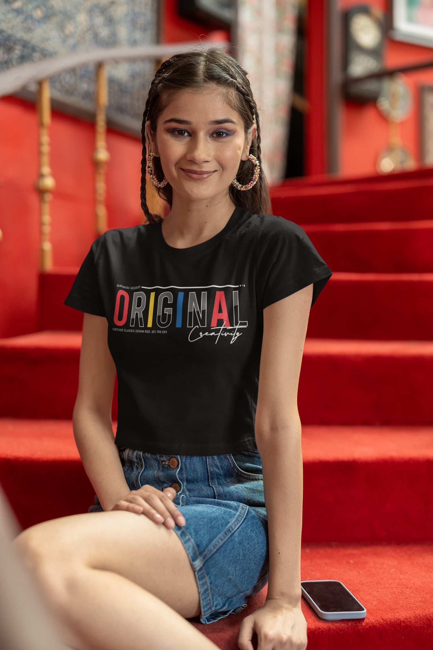 Woman wearing a black t-shirt with colorful text sitting on red steps.