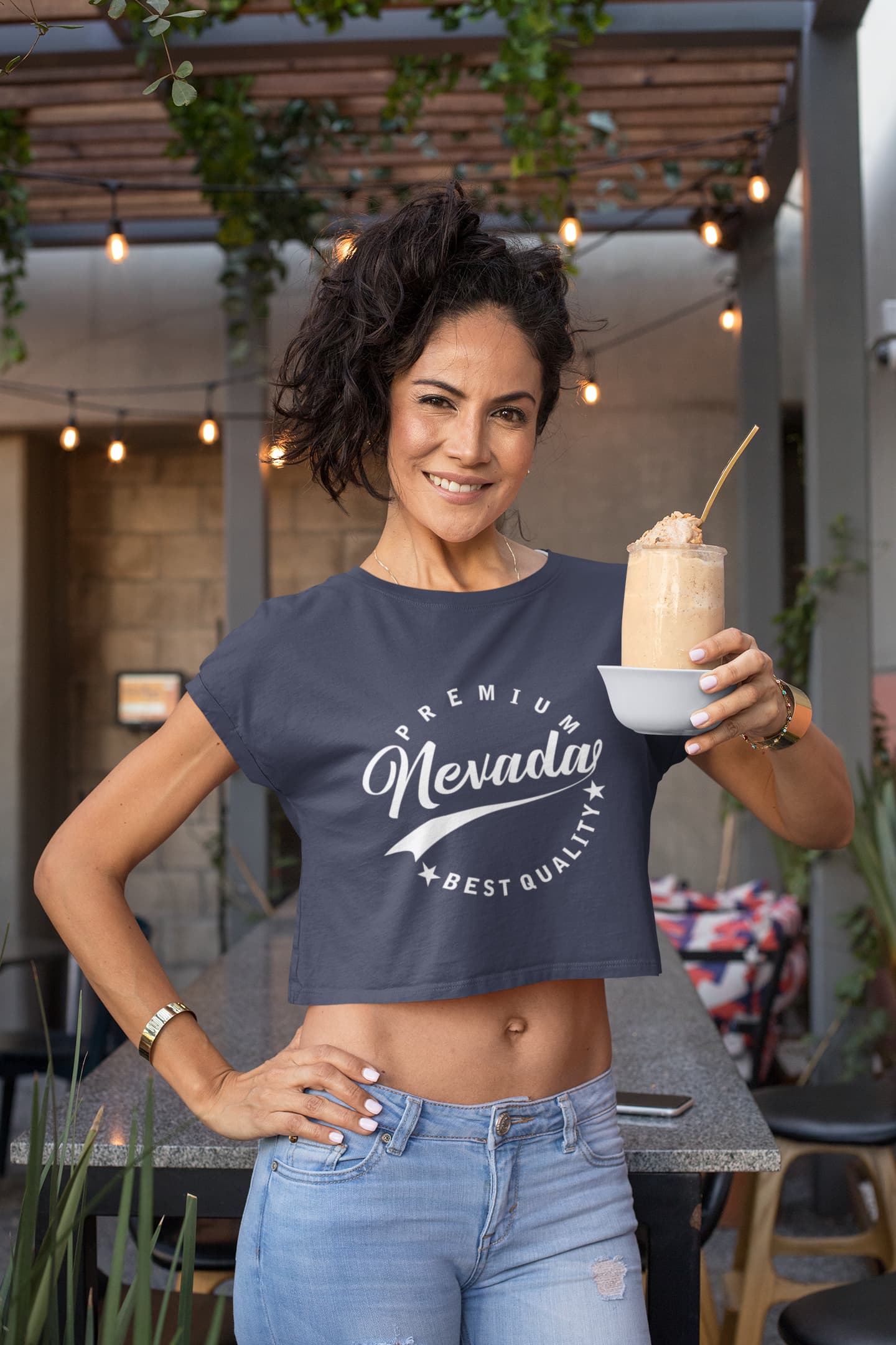 Woman holding a drink in an outdoor setting wearing a &