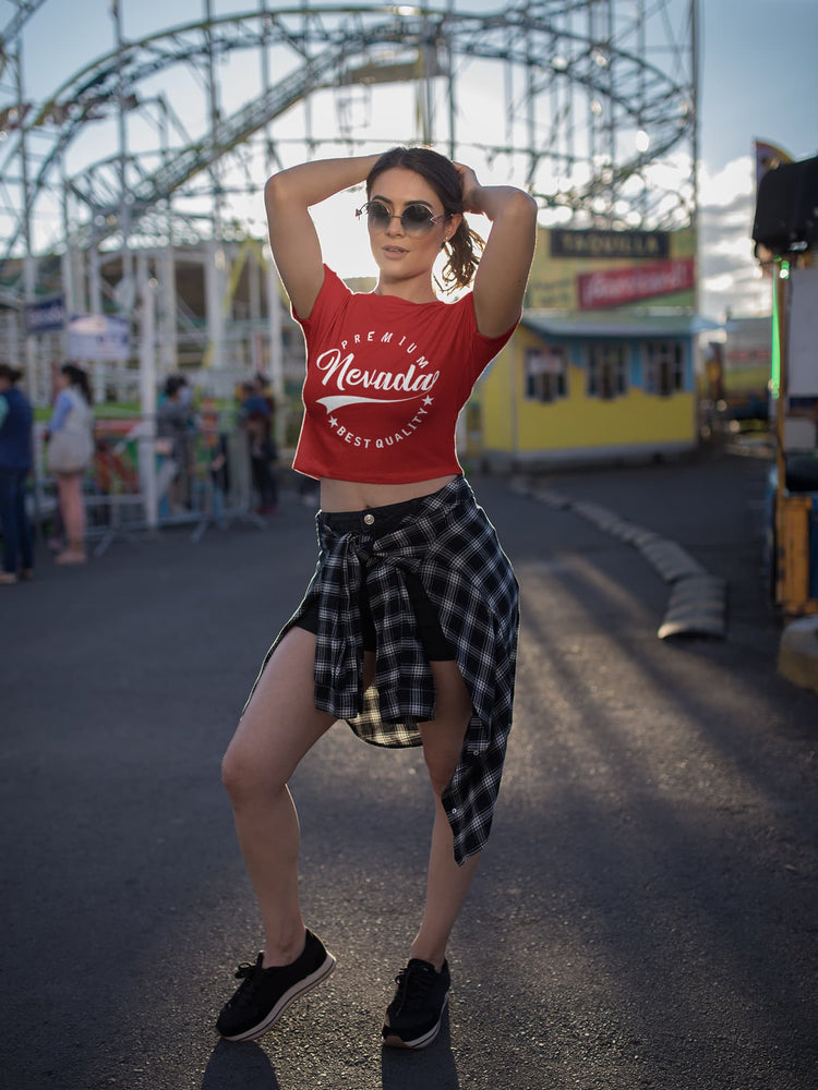 Woman in a red tank top and plaid skirt posing in front of an amusement park.