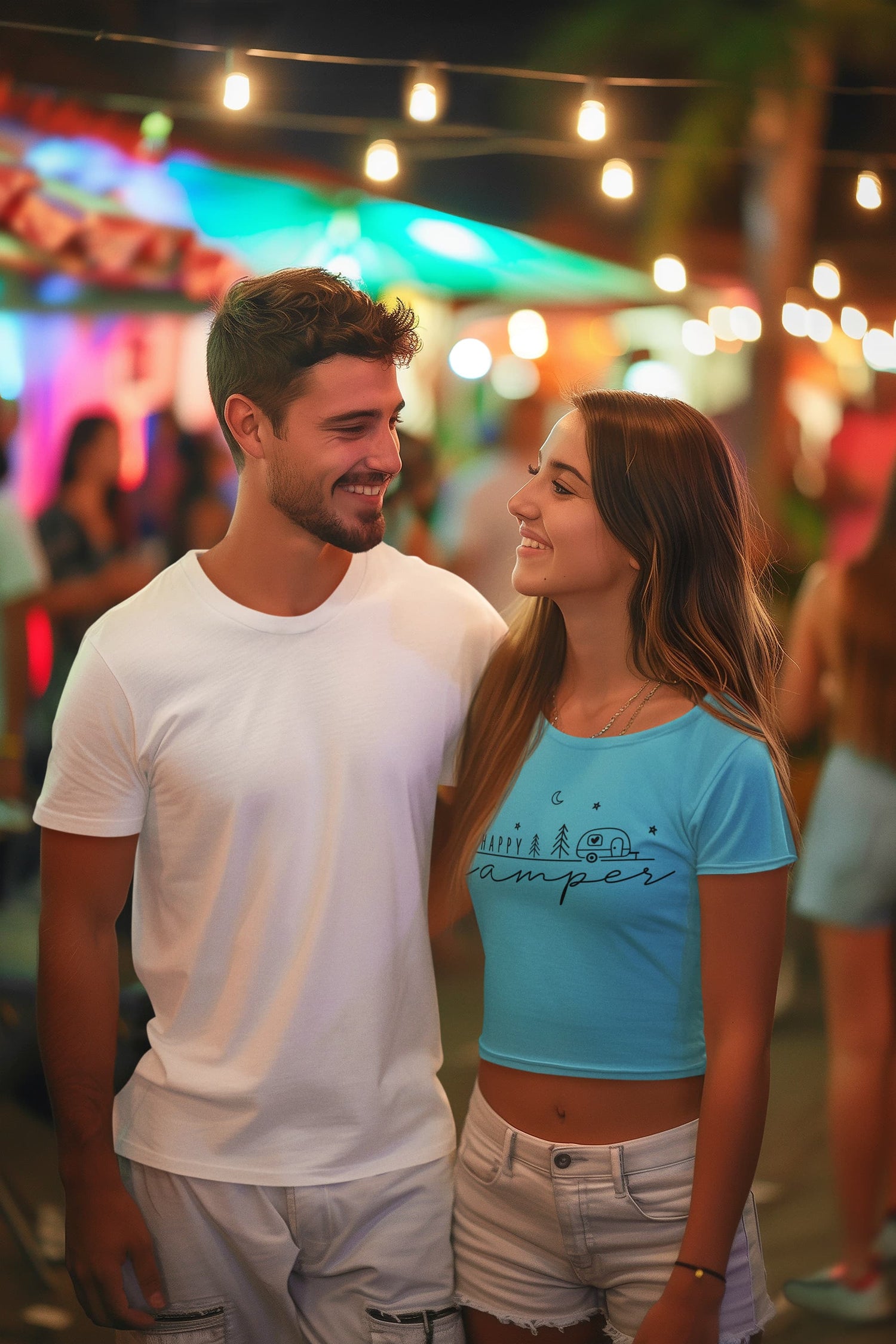 Couple standing together in a lively outdoor setting with string lights and people in the background.