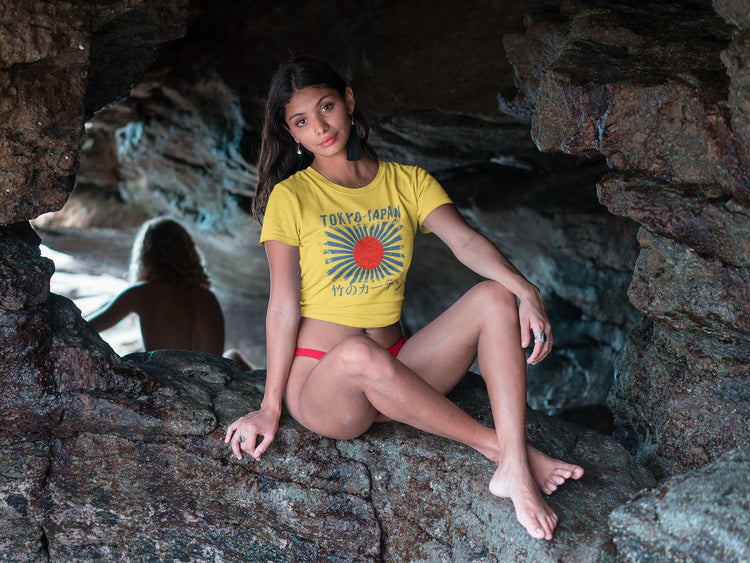 Woman in a yellow t-shirt with a graphic design sitting in a cave.