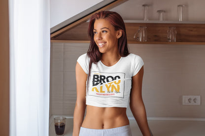 Woman wearing a white crop top with a graphic design in a kitchen.