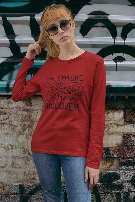 Person wearing a red long-sleeve shirt with text and graphic design, standing against a textured wall.