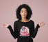 Woman wearing a black long-sleeve shirt with a pink flamingo graphic on a pink background