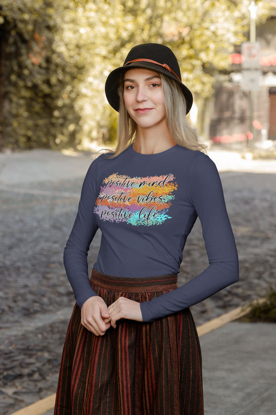 Woman wearing a long-sleeve shirt with a colorful design and text outdoors.