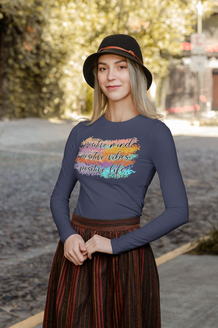 Woman wearing a long-sleeve shirt with a colorful design and text outdoors.