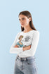 Woman wearing a white long-sleeve shirt with a graphic design on a light blue background
