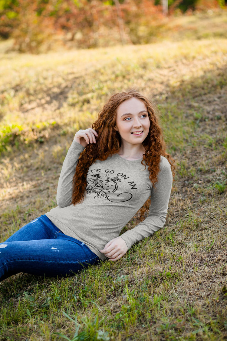 Woman sitting in a field wearing a graphic t-shirt with text and design.