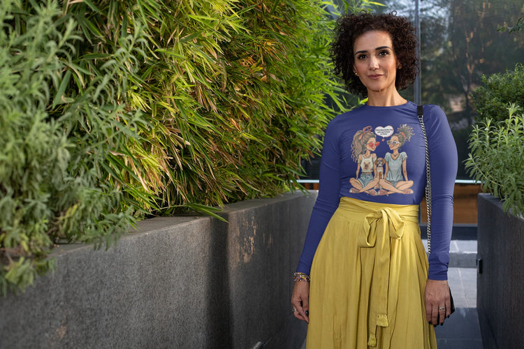 Woman wearing a blue top with a graphic design and a yellow skirt standing in front of green plants.