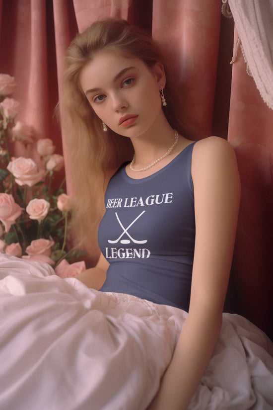 Woman wearing a blue tank top with text, sitting against a pink curtain with flowers.