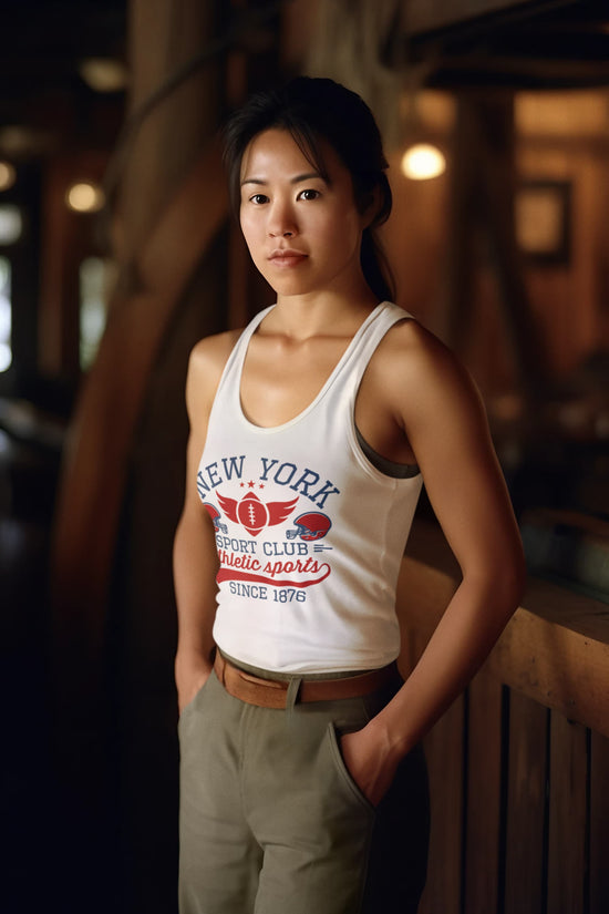 Woman wearing a white tank top with text and graphics, standing indoors.