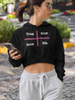 Woman wearing a black hoodie with text and gray sweatpants, holding a phone outdoors.
