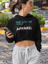 Woman wearing a black hoodie with text, holding a phone, standing outdoors.