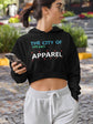 Woman wearing a black hoodie with text, holding a phone, standing outdoors.