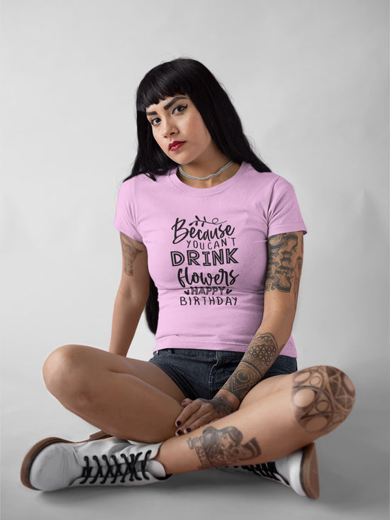 Person wearing a pink t-shirt with text, sitting on the floor against a plain background