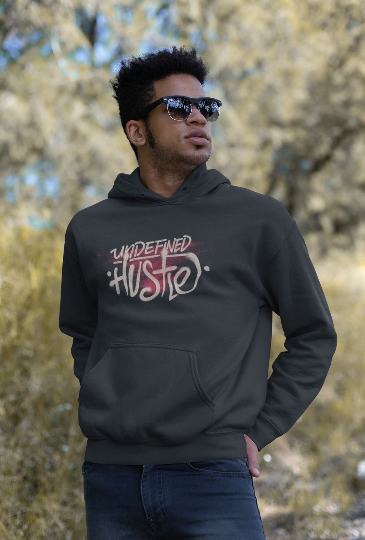 Man wearing a black hoodie with 'Undefined Hustle' text outdoors