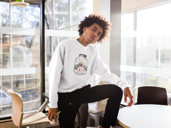 Person wearing a white sweatshirt with a design, sitting in a modern office setting.