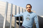 Man wearing a light blue sweater with a design, standing outdoors.
