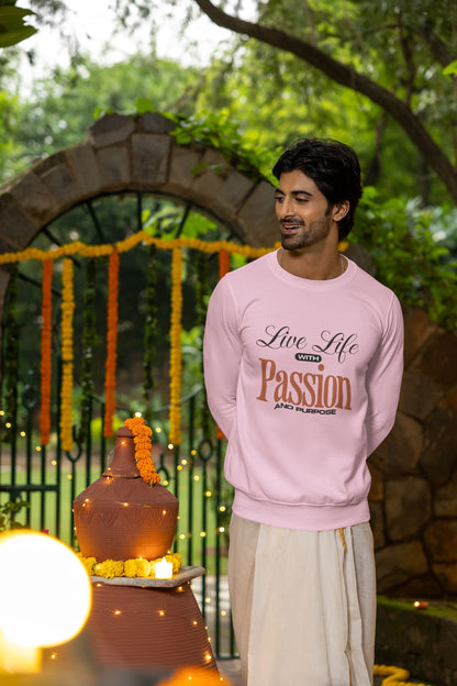 Man wearing a pink sweatshirt with text standing in front of a decorated archway.