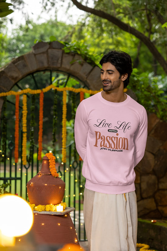 Man wearing a pink sweatshirt with text standing in front of a decorated archway.