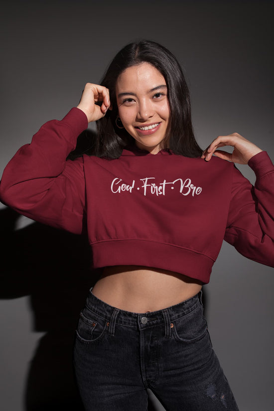 Person wearing a maroon cropped hoodie with text on a dark background