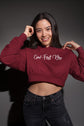 Person wearing a maroon cropped hoodie with text on a dark background