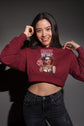 Woman wearing a maroon cropped hoodie with graphic design on a gray background