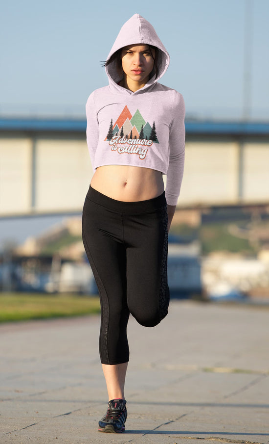 Person wearing a light pink hoodie with a nature-themed design and black leggings outdoors.