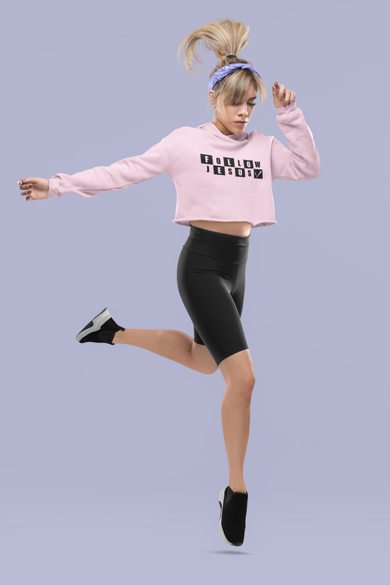 Person wearing a pink cropped sweatshirt and black leggings on a light purple background
