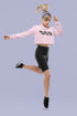 Person wearing a pink cropped sweatshirt and black leggings on a light purple background