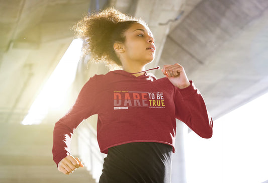 Person wearing a red hoodie with 'Dare to be True' text, running indoors.