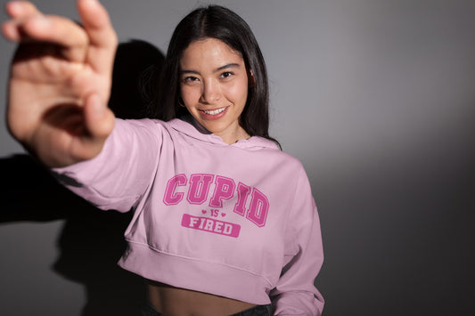 Person wearing a pink hoodie with 'CUPID IS FIRED' text on a dark background