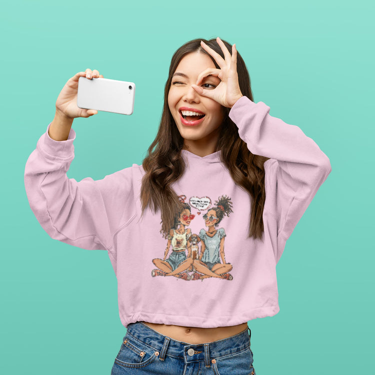 Woman wearing a pink sweatshirt with a graphic design, taking a selfie against a teal background