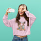 Woman wearing a pink sweatshirt with a graphic design, taking a selfie against a teal background